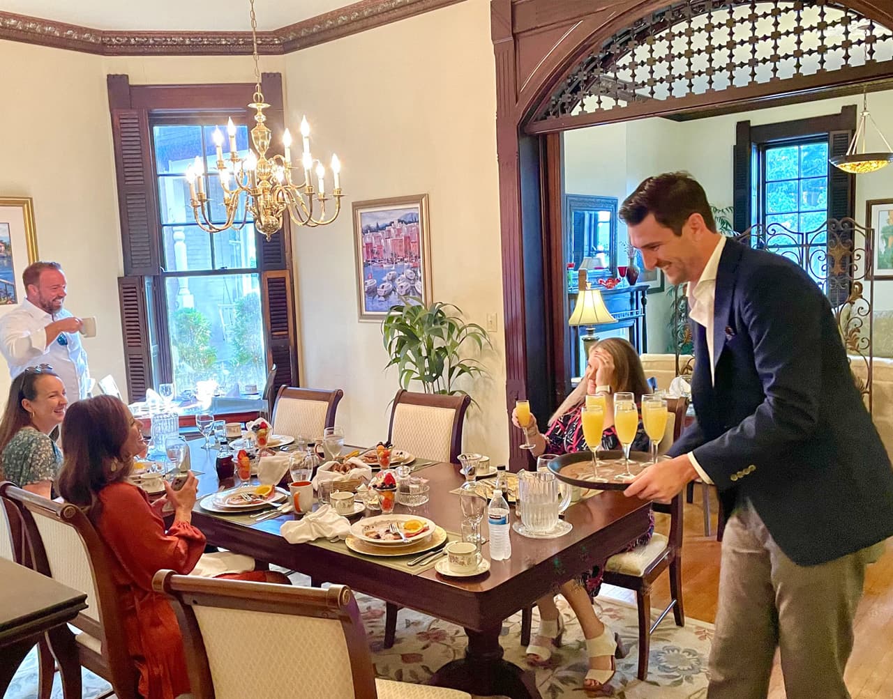 A group of people enjoys a meal together at a beautifully set dining table in a well-lit room.